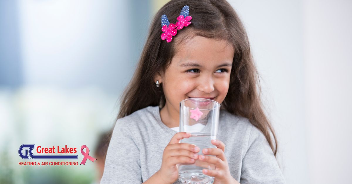 A young girl drinking a glass of water.